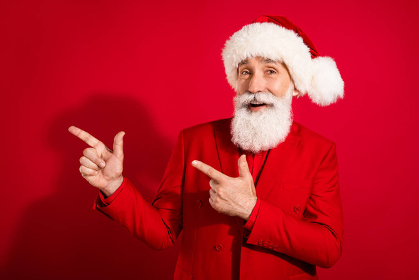 Photo of old happy man point finger empty space good mood xmas celebrate isolated on red color background - Fotografie, Obrázek