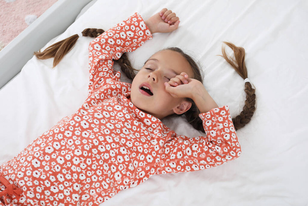 Sleepy girl in pajamas on bed at home - Fotoğraf, Görsel
