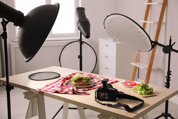 Professional camera and composition with tasty sandwich on table in photo studio. Food photography - 写真・画像