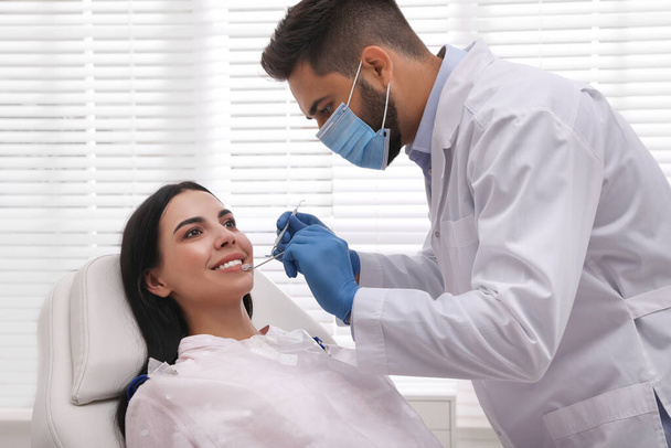 Dentist examining young woman's teeth in modern clinic - Фото, изображение