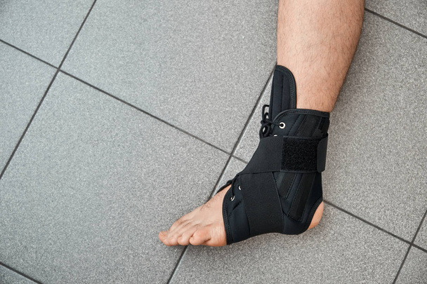 The male leg is fixed in a medical bandage. Ankle fracture or sprain. Lacing and tight fit of the foot. A healthy and diseased part of body. Post-fracture therapy and development. Treatment accesuare. - Valokuva, kuva