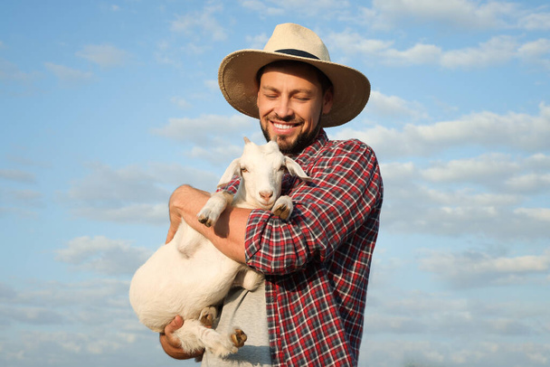 Farmer with cute goatling outdoors. Baby animal - Zdjęcie, obraz