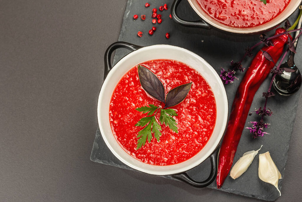 Spicy autumn tomato soup. Healthy hot food, garlic, chili, basil. Black stone concrete background, top view - Fotografie, Obrázek