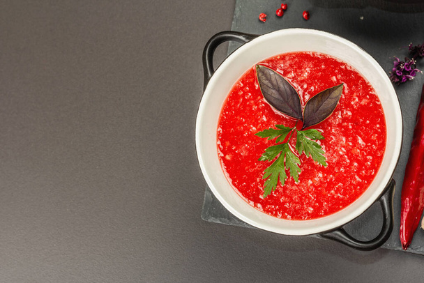 Spicy autumn tomato soup. Healthy hot food, garlic, chili, basil. Black stone concrete background, top view - Photo, Image