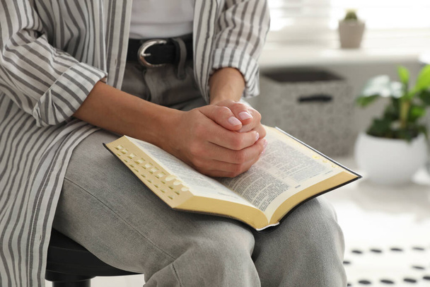 Young woman praying over Bible at home, closeup - Photo, image