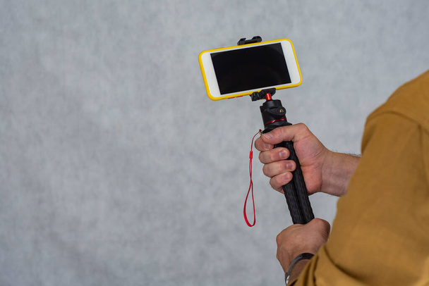 Un homme tient un trépied flexible avec une maquette d'un smartphone avec un écran noir - Photo, image