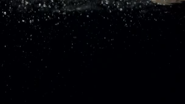 Hidasliikkeiset ilmakuplat vedessä nousevat pintaan mustalla pohjalla - Materiaali, video