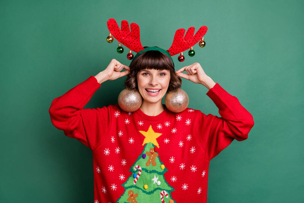 Portrait of attractive cheerful girl wearing festal look tree balls like earrings isolated over green color background - 写真・画像