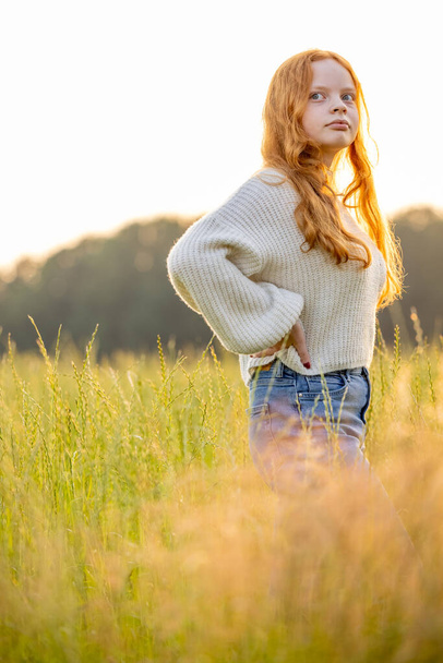 Fall fashion concept. Beautiful young woman in a cozy knitted sweater. Outdoor photo of funny hipster girl wearing trendy casual outfit. Warm light sunset - Photo, Image