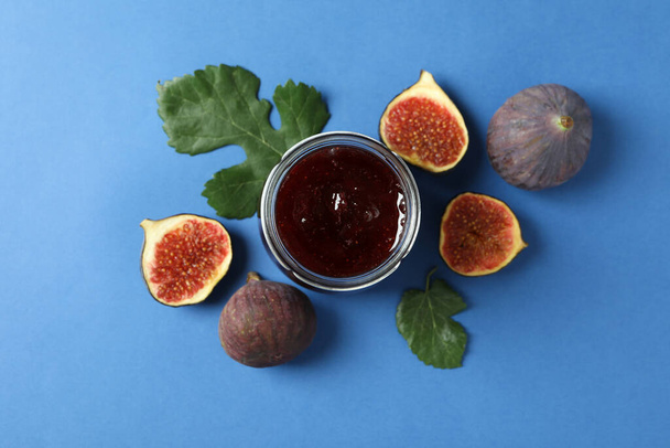 Jars with fig jam and ingredients on blue background - Photo, Image