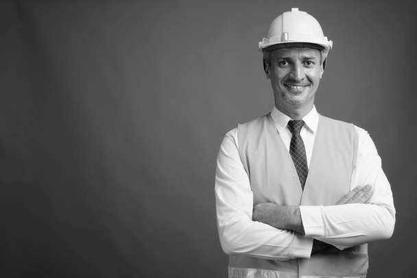 Studio shot of man construction worker against gray background in black and white - Foto, afbeelding