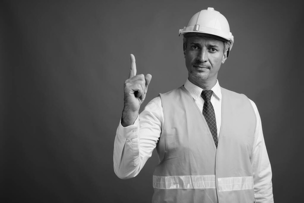 Estudio de hombre trabajador de la construcción sobre fondo gris en blanco y negro - Foto, Imagen