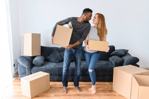 Happy African-American boyfriend and charming caucasian girlfriend is unpacking - Photo, Image