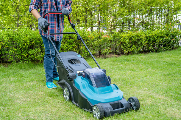 Gardener use lawn mover machine cut green grass, Hobby planting home garden. - Zdjęcie, obraz