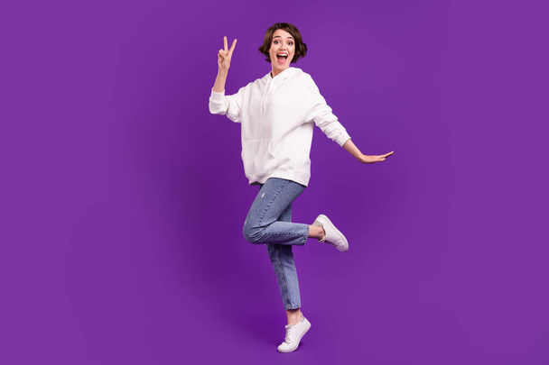 Full length body size photo girl smiling in casual clothes showing v-sign isolated vivid purple color background - Фото, изображение