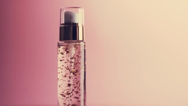 Produkt do pielęgnacji skóry w złotej butelce na różowym tle - Materiał filmowy, wideo