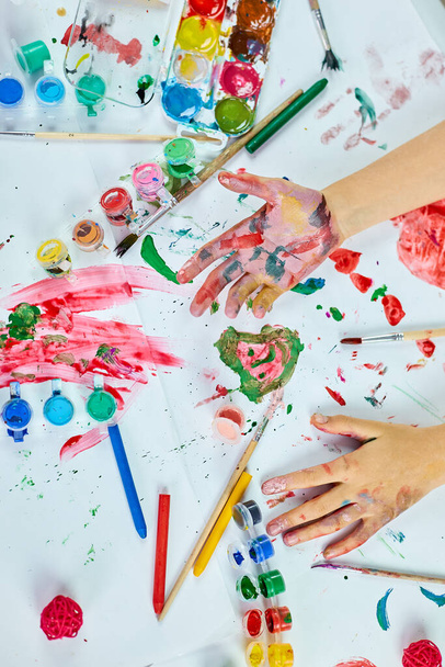 Top view Mała dziewczynka z malowane kolorowe ręce akwarela, dziecko siedzi przy stole i rysunek, koncepcja szkoły artystycznej, malowanie dziecko dziewczyna w domu - Zdjęcie, obraz
