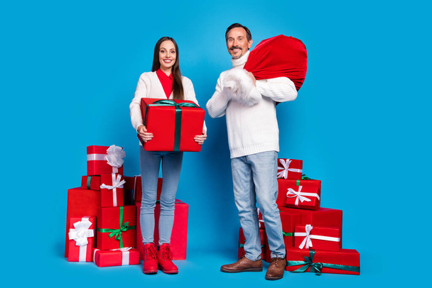 Full length body size view of attractive cheerful couple holding giftboxes winter day isolated over bright blue color background - Foto, imagen