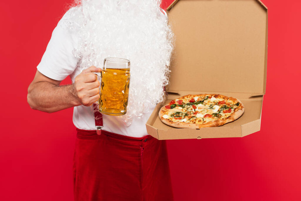 Cropped view of santa claus holding beer and pizza in box isolated on red  - Foto, immagini