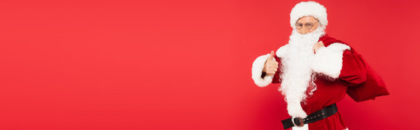 Santa claus holding sack and showing like isolated on red, banner  - Фото, зображення