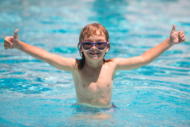 Child boy swim in swimming pool. Excited child in sunglasses in pool in summer day. - Zdjęcie, obraz