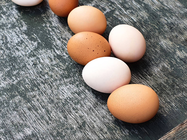 Huevos blancos y marrones de gallinas domésticas sobre fondo de textura pintada gris madera vieja. Primer plano. - Foto, Imagen