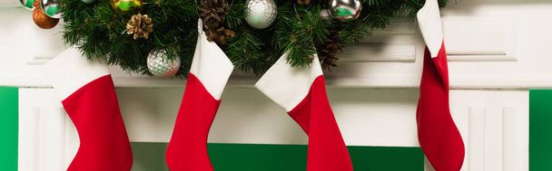 Weihnachtsstrümpfe und Tannenzweige am Kamin auf grünem Hintergrund, Banner  - Foto, Bild