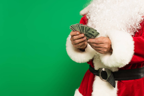Cropped view of santa claus in costume holding dollars isolated on green - Foto, afbeelding