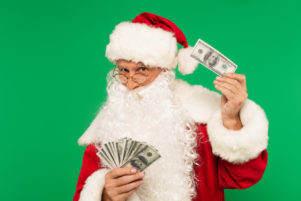 Bärtiger Weihnachtsmann hält Bargeld isoliert auf Grün - Foto, Bild