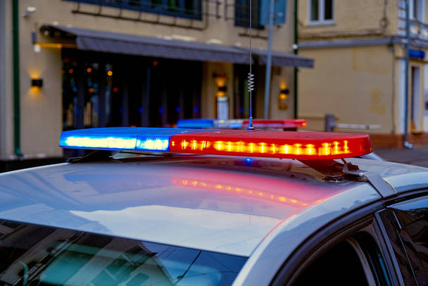 Red and blue flashing lights on police car on evening street. - Fotoğraf, Görsel