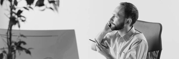 Young business man working at office, making phone call. Career concept. Black and white effect - Фото, изображение