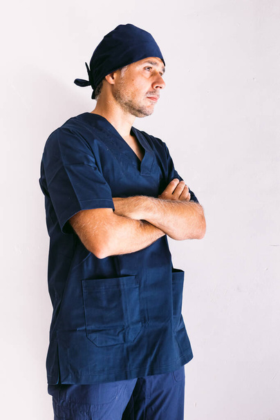Мужчина медбрат, врач или ветеринар в темно-синей униформе в больнице, руки скрещены. Медицина, больница и здравоохранение. - Фото, изображение