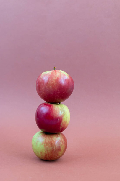 Пачка красных свежих яблок балансирует на коричневом фоне - Фото, изображение
