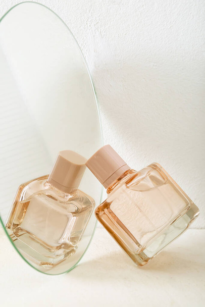 Butelka perfum odbijająca się w lustrze na stole - Zdjęcie, obraz
