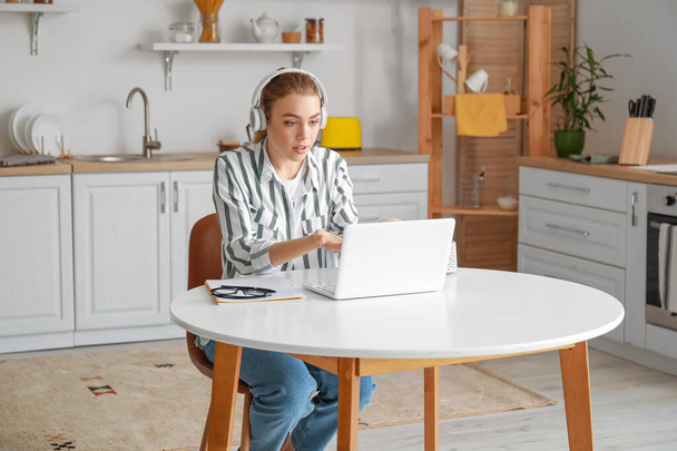 Young woman with laptop video chatting in kitchen - Foto, imagen