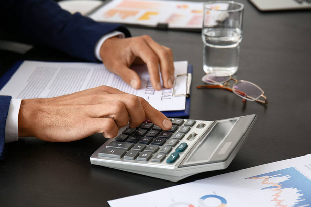 Бизнесмен использует калькулятор в офисе, крупным планом - Фото, изображение