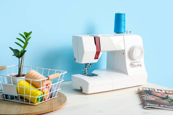 Máquina de coser moderna en la mesa cerca de la pared azul - Foto, Imagen