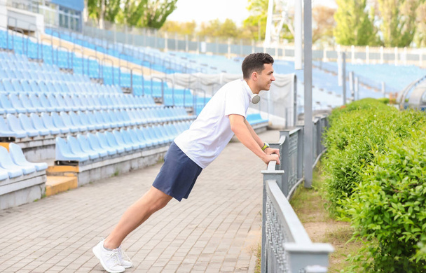 Спортивний молодий чоловік робить поштовхи на стадіоні
 - Фото, зображення