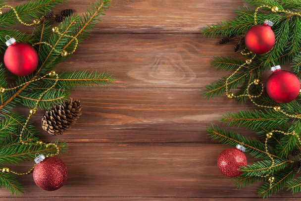 Spruce branches with red Christmas balls on a wooden background. Christmas and New Year concept. Horizontal orientation, copy space, top view. - Photo, Image