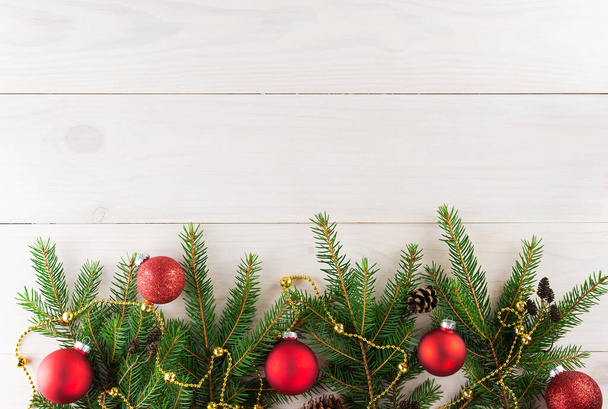 Spruce branches with red Christmas balls on a white wooden background. Christmas and New Year concept. Horizontal orientation, copy space, top view. - 写真・画像