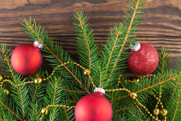 Smrkové větve s červenými vánočními míčky na hnědém dřevěném pozadí. Koncept Vánoc a Nového roku. Vodorovná orientace, pohled shora. - Fotografie, Obrázek