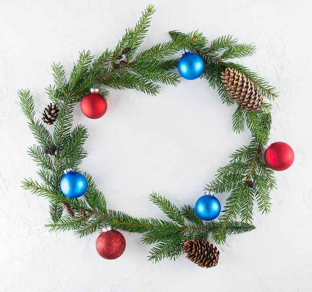 A wreath of fir branches, decorated with Christmas balls and cones on a white background. Christmas and New Year concept, top view. - Photo, image