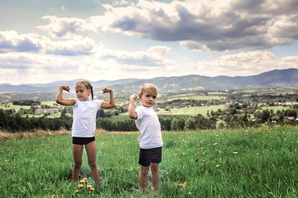 Menino e menina fazendo os exercícios matinais com halteres no topo das montanhas no verão - Foto, Imagem