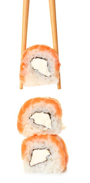 Chopsticks tomando delicioso rolo de sushi da pilha no fundo branco - Foto, Imagem