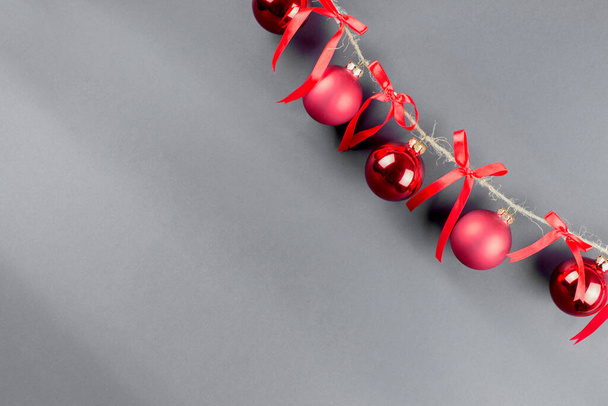 draad met rode kerstballen en rode strikken op zwarte achtergrond - Foto, afbeelding