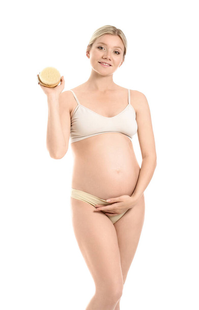 Krásná těhotná mladá žena s masážním štětcem na bílém pozadí - Fotografie, Obrázek