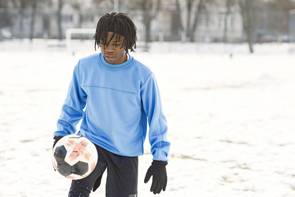 African american man playing soccer on winter day - Фото, зображення