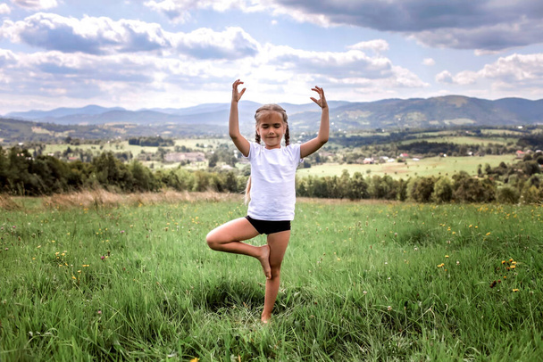 Приваблива дівчина робить ранкові вправи на вершині гір в літній природі
 - Фото, зображення