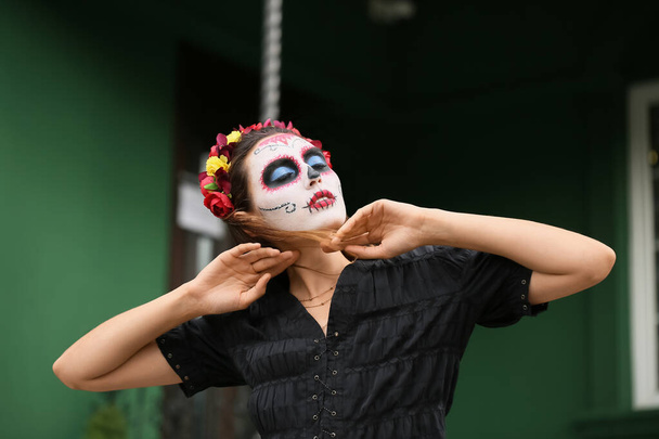 Fiatal nő, festett koponyával az arcán a szabadban. Mexikó holtak napjának ünneplése (El Dia de Muertos) - Fotó, kép