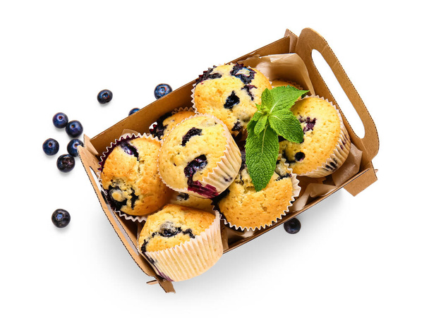 Boîte avec de savoureux muffins aux myrtilles sur fond blanc - Photo, image